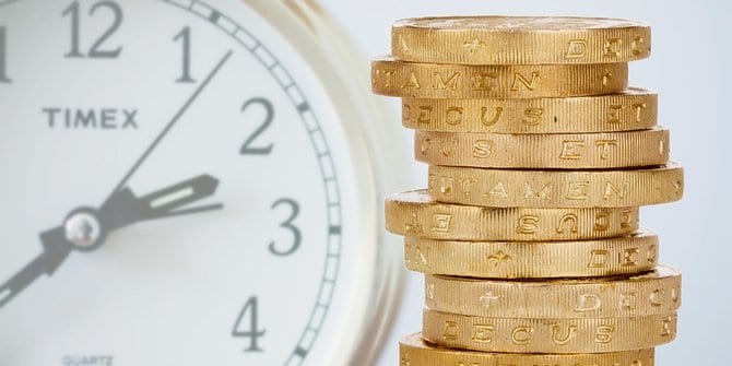 tumpukan koin dan jam melambangkan manfaat investasi dalam jangka panjang