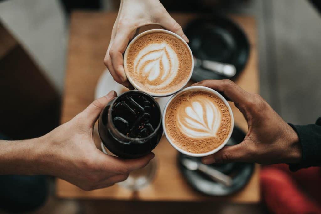 Tiga orang mengangkat kopi untuk Minum Kopi Sebelum Olahraga