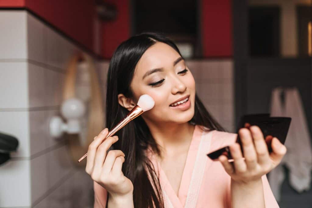 Seorang wanita yang sedang melakukan make up dengan urutan make up pemula